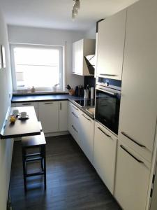 una cucina con armadi bianchi, tavolo e piano cottura di Geräumige schöne Ferienwohnung stadtnah ruhig Nähe Bodensee mit Aussicht a Weingarten