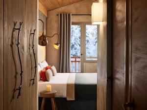 um quarto com uma cama e uma janela em Hôtel L'Arboisie em Megève