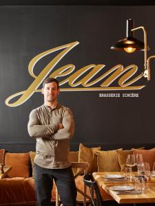 un homme debout devant un restaurant avec les bras croisés dans l'établissement Hôtel L'Arboisie, à Megève