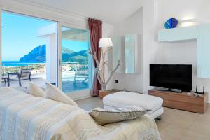 1 dormitorio con 1 cama, TV y balcón en Villa Marconi Apartment 12 attico, en Golfo Aranci