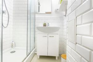 a white bathroom with a sink and a shower at Sielecka 52 - 4os apartament in Warsaw