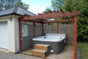 a hot tub on a deck with a wooden pergola at Glan yr Afon in Dolgellau in Dolgellau