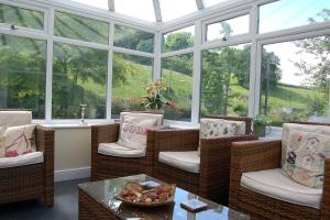 a conservatory with chairs and a table and windows at Glan yr Afon in Dolgellau in Dolgellau