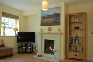 a living room with a fireplace and a flat screen tv at Glan yr Afon in Dolgellau in Dolgellau