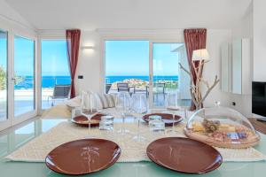 un comedor con una mesa con copas de vino y el océano en Villa Marconi Apartment 12 attico, en Golfo Aranci