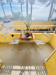 a table and chairs on a balcony with palm trees at La Ciotat vue mer emplacement exceptionnel avec parking in La Ciotat