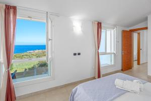 1 dormitorio con cama y ventana grande en Villa Marconi Apartment 12a attico, en Golfo Aranci
