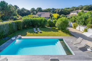 uma piscina num quintal com cadeiras e árvores em Pyla Belle villa au calme Proche plage em Pyla-sur-Mer