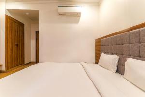 ein Schlafzimmer mit einem großen Bett mit weißer Bettwäsche und Kissen in der Unterkunft FabExpress Global Inn New in Lucknow