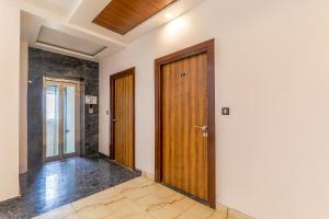 a hallway with two wooden doors and marble floors at FabExpress Global Inn New in Lucknow