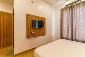 ein Schlafzimmer mit einem Bett und einem TV an der Wand in der Unterkunft FabExpress Global Inn New in Lucknow