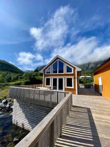 a small house with a wooden deck and glass windows at Fjordview Ryten 1 Retreat in Sund