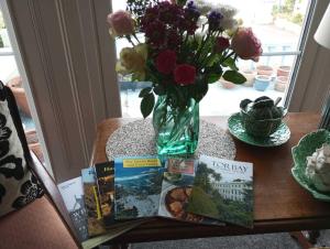 a table with a vase of flowers and books on it at Garway Lodge Guest House in Torquay