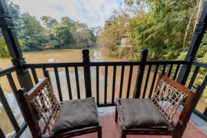 2 Stühle auf einem Balkon mit Flussblick in der Unterkunft Siddhartha Vilasa Banbas, Chitwan in Chitwan