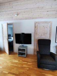 a living room with a chair and a flat screen tv at Semesterhus med spabad & bastu in Söderköping