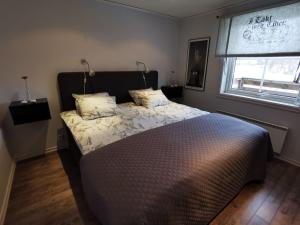 1 dormitorio con 1 cama con 2 almohadas y ventana en Semesterhus med spabad & bastu en Söderköping