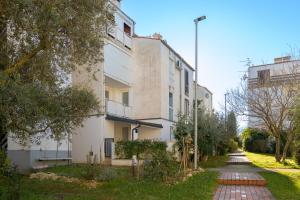 a white building with a sidewalk in front of it at Apartment Pinjola in Poreč
