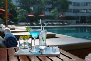 a tray with a margarita and a drink on a table by a pool at Amari Don Muang Airport Bangkok in Bangkok
