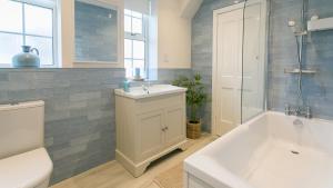 a bathroom with a tub and a sink and a toilet at Ty Draw in Abersoch +23 photos