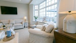 a living room with white furniture and a large window at Ty Draw in Abersoch