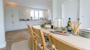a kitchen with a wooden table with chairs and a counter top at Ty Draw in Abersoch
