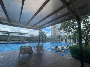 a large swimming pool with two chairs and a wooden deck at 42nd Floor Condo with Pool at Horizon 101 Tower 2 in Cebu City