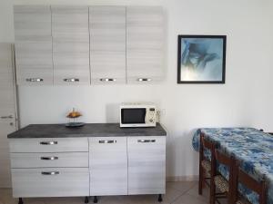 a room with a counter with a microwave and a table at Ancora: appartamenti Gaudenzi in Gabicce Mare +8 photos