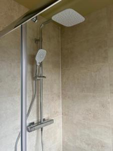 a shower with a shower head in a bathroom at Woodstock by Spires Accommodation a uniquely Retro place to stay near Wolverhampton in Codsall