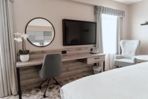 a bedroom with a desk with a television and a mirror at Cabarfeidh Hotel in Stornoway