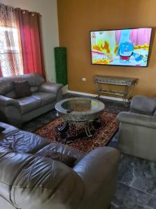 a living room with couches and a flat screen tv at Home away from Home in Dabadie