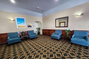 a waiting room with blue chairs and a mirror at Days Inn & Suites by Wyndham Pasadena in Pasadena