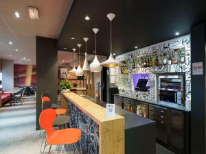 a restaurant with a bar with orange chairs at ibis Saint Quentin Basilique in Saint-Quentin