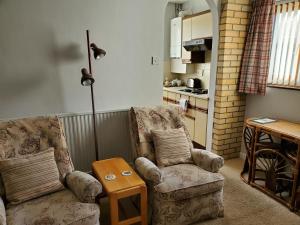 a living room with two chairs and a table at Cae y Rhedyn Annexe in Crickhowell