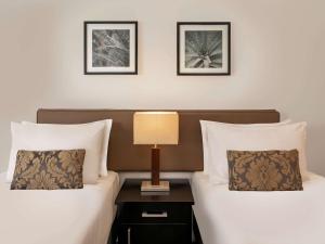 duas camas num quarto de hotel com um candeeiro numa mesa de cabeceira em Novotel Suva Lami Bay em Suva
