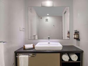 a bathroom with a sink and a large mirror at Novotel Suva Lami Bay in Suva