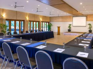 une salle de conférence avec des tables, des chaises et un écran dans l'établissement Novotel Suva Lami Bay, à Suva