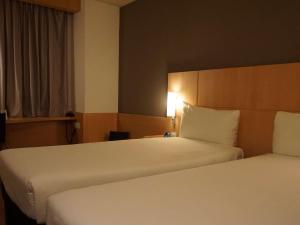 a hotel room with two beds and a lamp at Ibis Girona in Girona