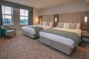 a hotel room with two beds and a chair at Best Western Clifton Hotel in Folkestone