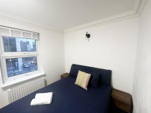 a bedroom with a blue bed with a window at Flat 3 Stay In Aldgate Apartments in London