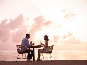 mężczyzna i kobieta siedzący przy stole na plaży w obiekcie Sofitel Bali Nusa Dua Beach Resort w mieście Nusa Dua