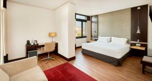 um quarto de hotel com uma cama, uma secretária e uma cadeira em NH Avenida Jerez em Jerez de la Frontera