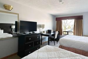 a hotel room with two beds and a desk with a television at Travelodge by Wyndham Welland in Welland