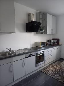 uma cozinha com armários brancos e um lavatório em Ferienwohnung Hellweg em Herford