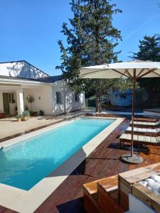 - une piscine avec un parasol et des chaises dans l'établissement Casita de Invitados con entrada privada, piscina y aire acondicionado, à Valdemorillo