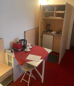 a small room with a table and a kitchen with a red table at Gästehaus Niki in Tauberbischofsheim