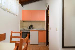 a small kitchen with orange cabinets and a table at Apartment Pinjola in Poreč