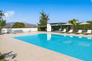 - une piscine avec des chaises et des parasols à côté dans l'établissement Villa Greta, à Fiumefreddo di Sicilia