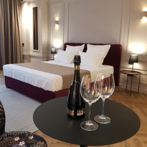 a bedroom with a bed with a bottle of wine and two glasses at Boutique ALNIS in Constanţa
