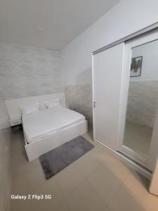 NgorにあるParadis Appartementのベッドと窓のある白い部屋