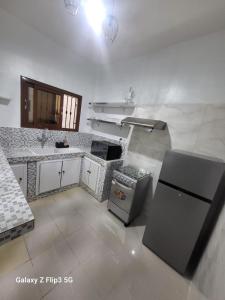 a kitchen with a black refrigerator and a sink at Paradis Appartement in Ngor